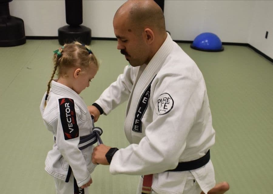 An instructor tying a child’s first belt at Pure Life
